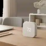 Un capteur de température élégant posé dans un bureau moderne pour illustrer la maîtrise du confort thermique. L’ambiance est sobre, premium et orientée usage quotidien.