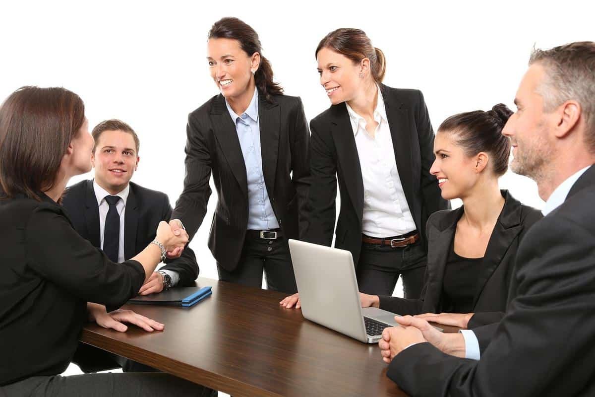 Groupe de professionnels en tenue formelle discutant autour d'une table avec ordinateur portable