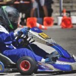 Un pilote en combinaison bleue pilote un kart sur circuit
