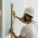 Un ouvrier en sécurité mesure verticalement un panneau de plâtre