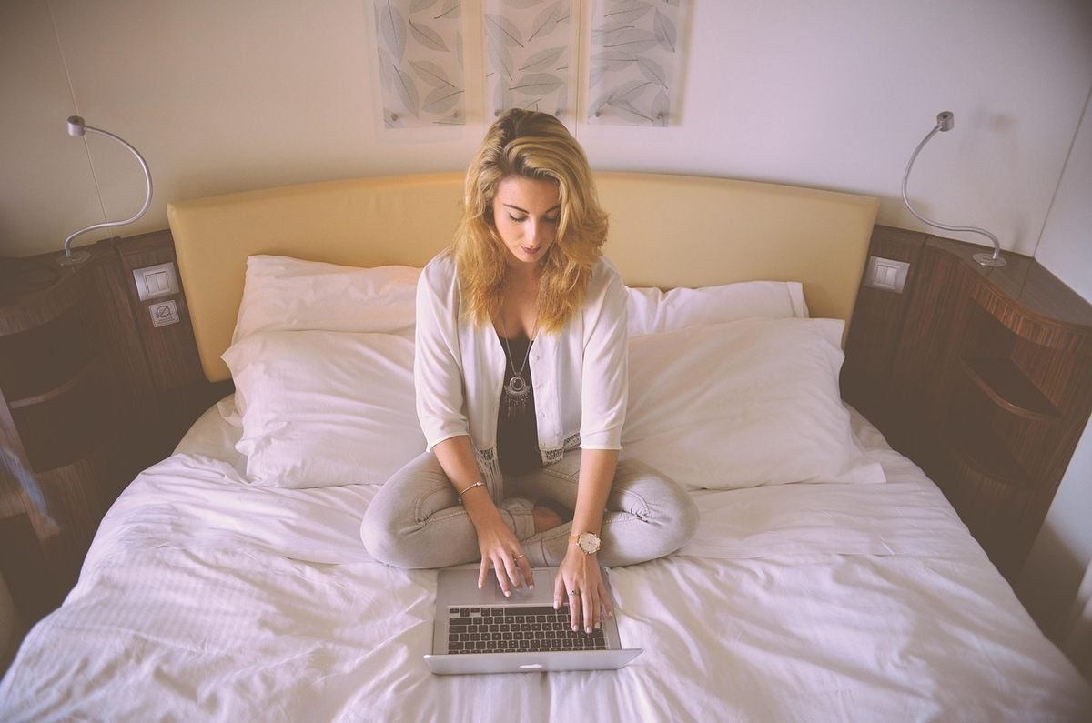 Femme sur un lit avec un ordinateur portable