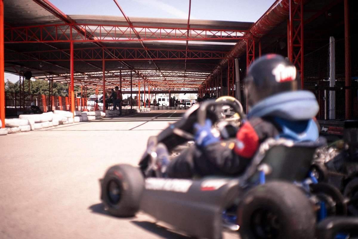 Un conducteur en kart sur piste couverte sous structure rouge