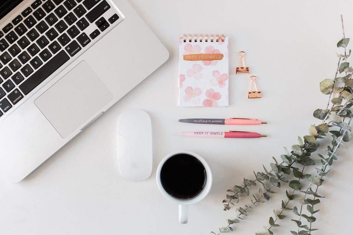 Bureau avec ordinateur, café, stylos, papier et plantes