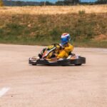 Un pilote de karting en tenue jaune et casque coloré sur piste